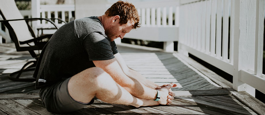 A young man performing a stretch on his deck in the morning hours.