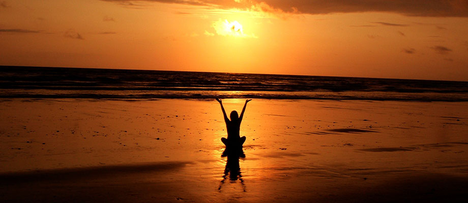 A young woman doing yoga on the beach during sunset.