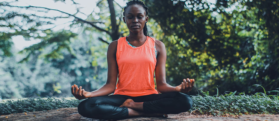 Young African American woman performing yoga outside in nature.