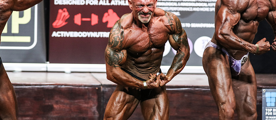 A tattooed man flexing during a Bodybuilding competition.